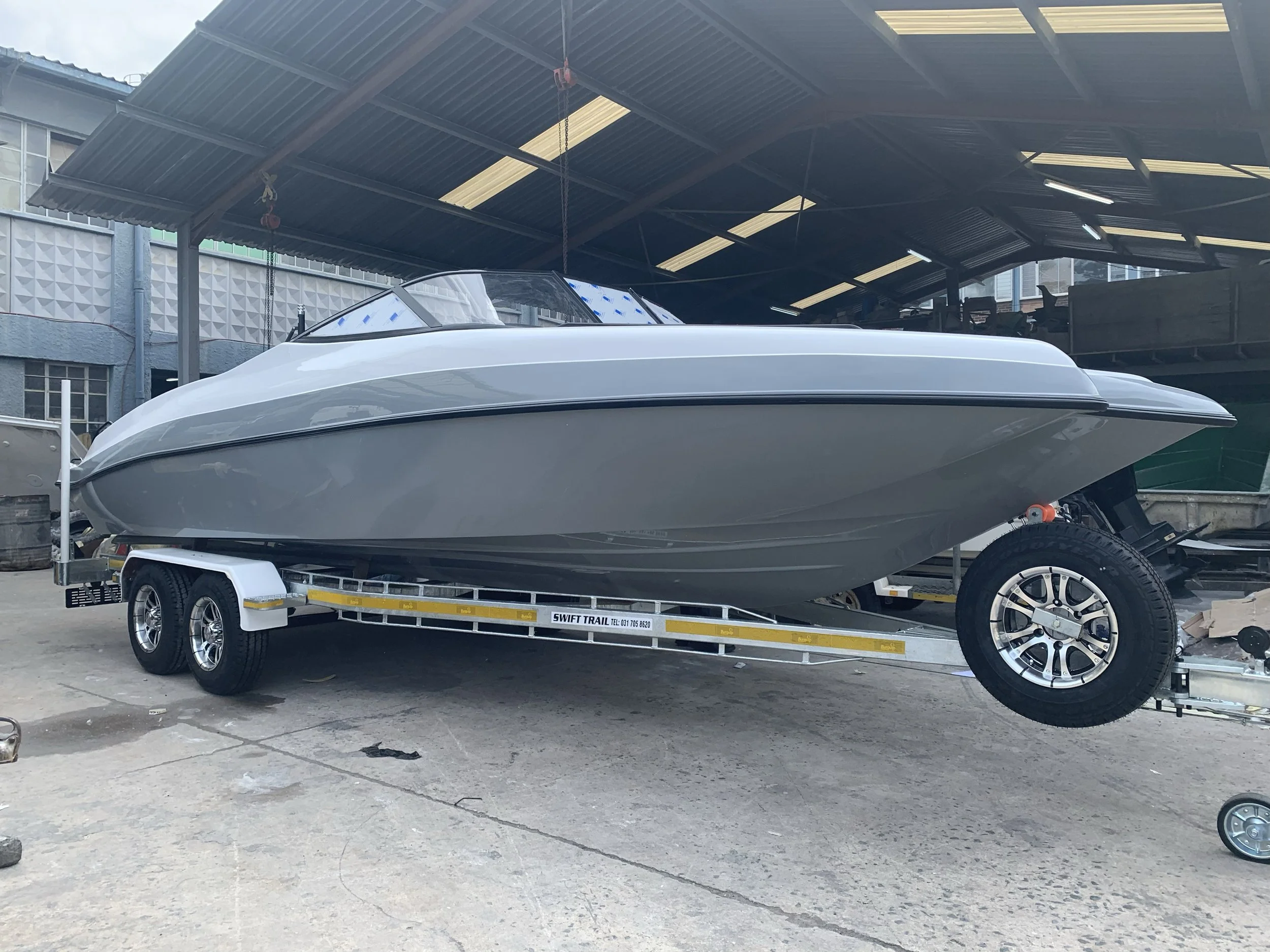 Gray speedboat on a trailer in a covered outdoor area.