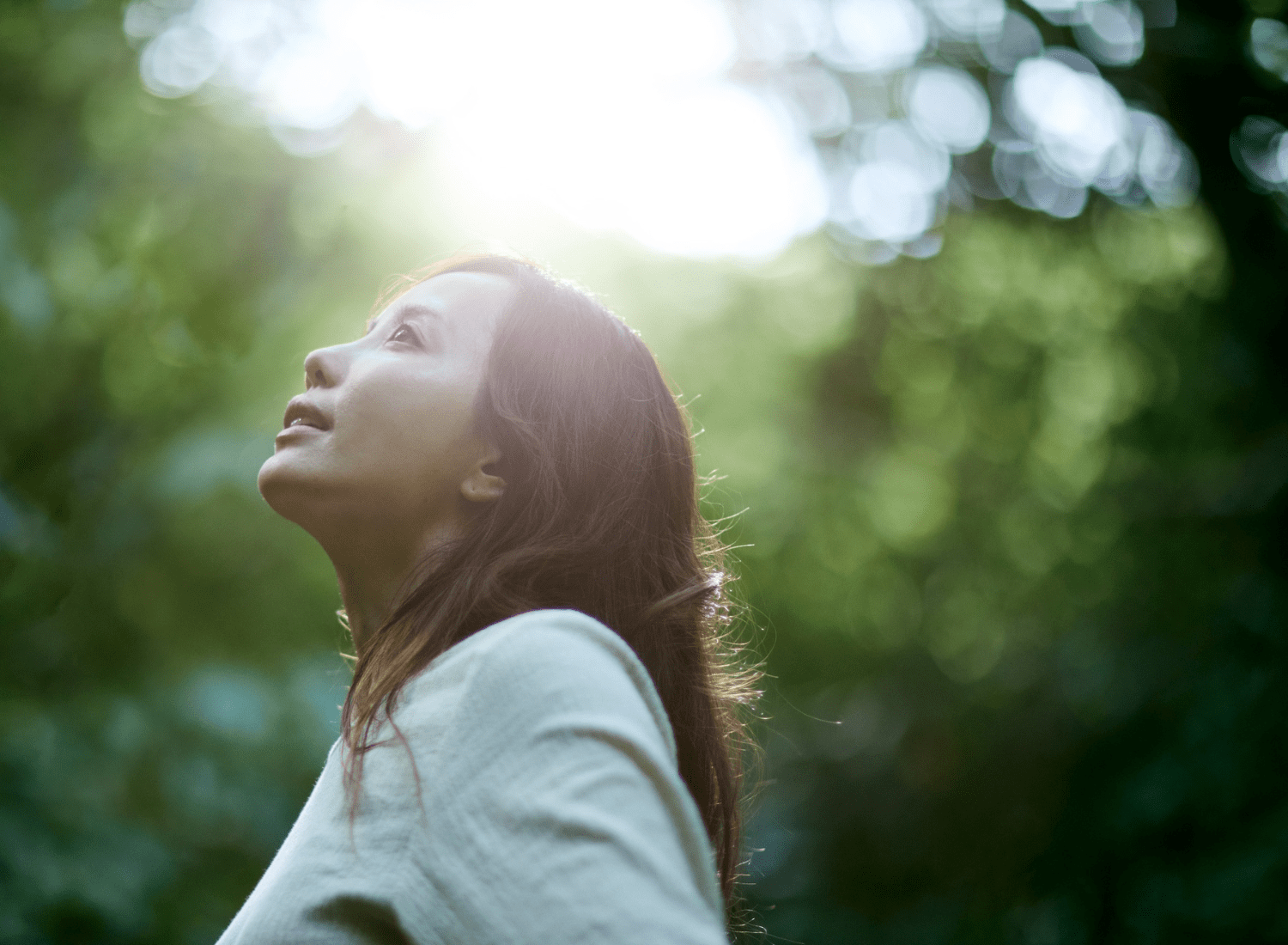 Woman standing in forest looking at sunlight