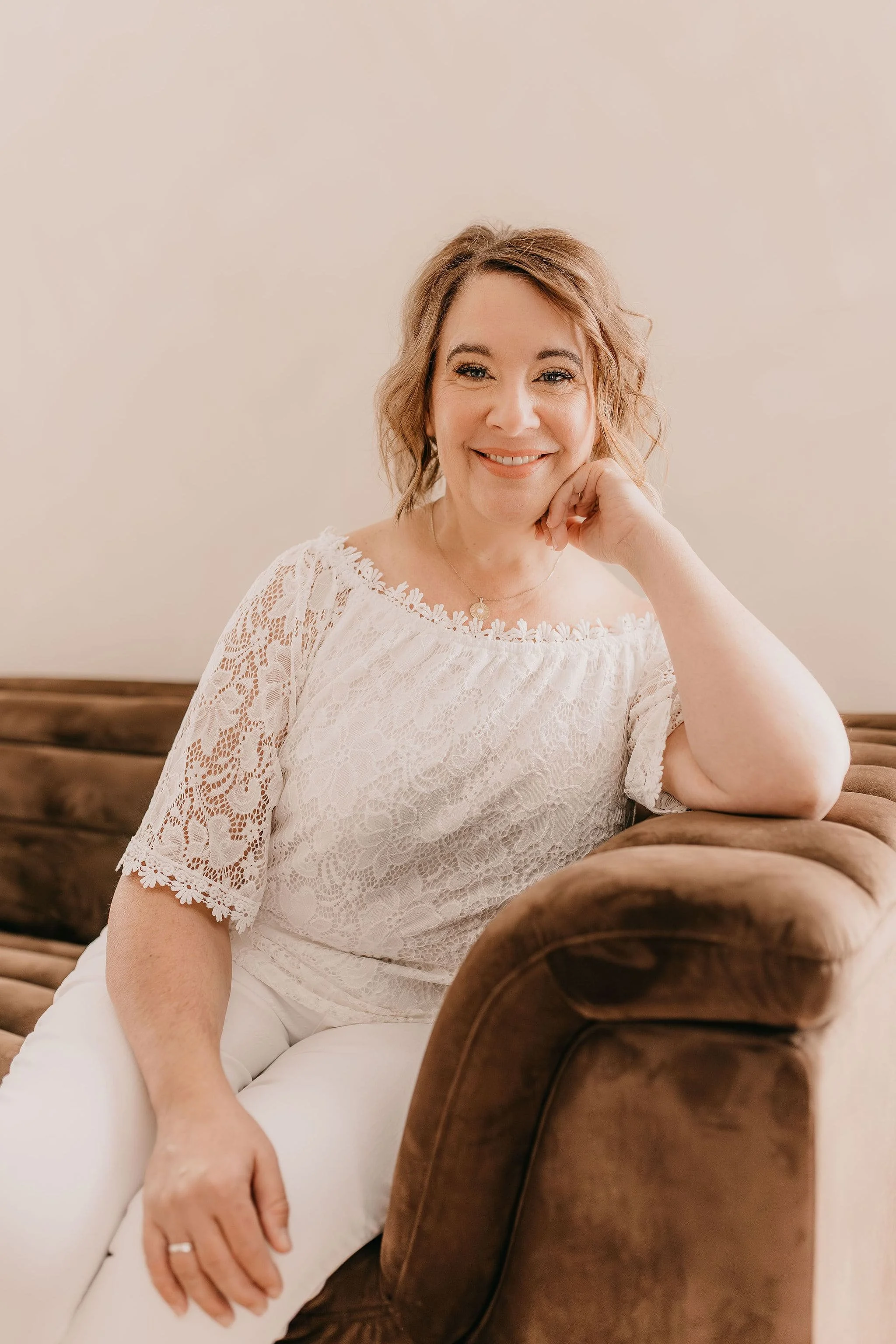 Melisa sitting on sofa in white outfit