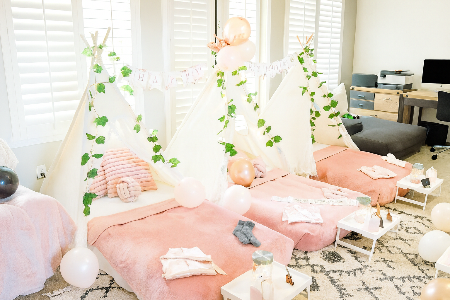 A birthday setup in a living room with pink and white tents, balloons, and decorations, set up for a celebration.