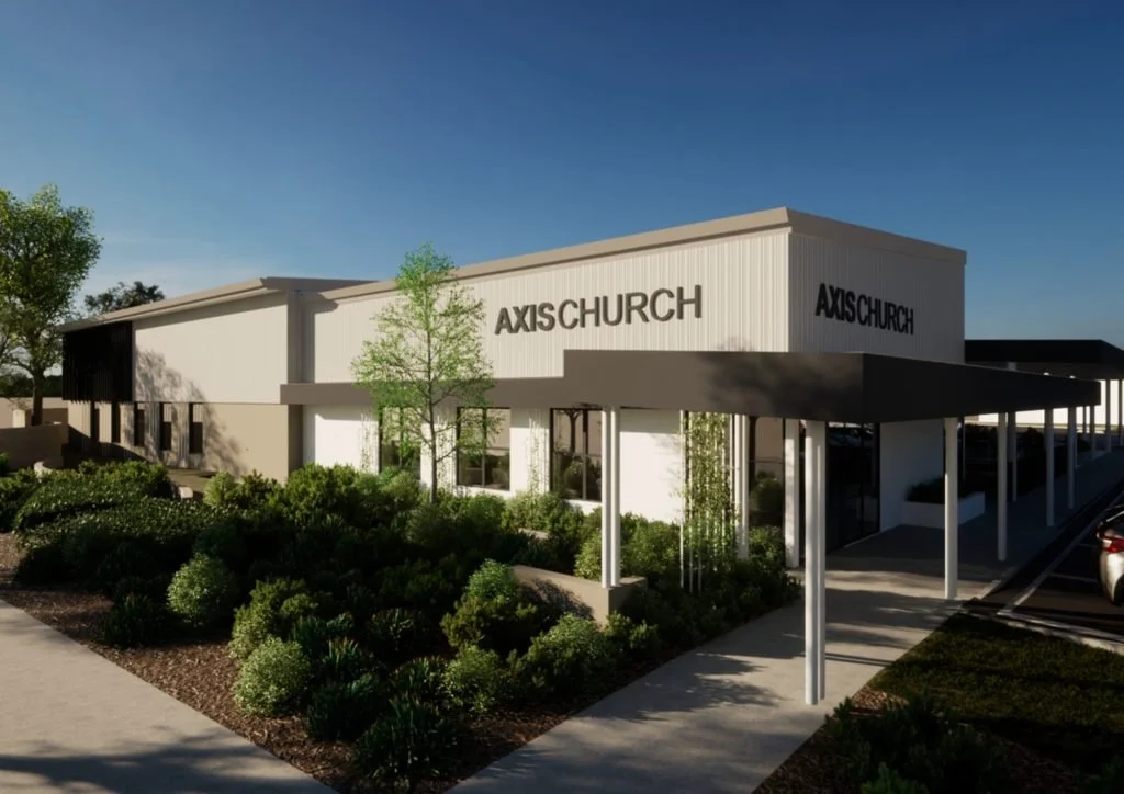 Modern church building with white exterior, black signage labeled "AXIS CHURCH," a covered walkway, surrounded by landscaping with bushes and trees.