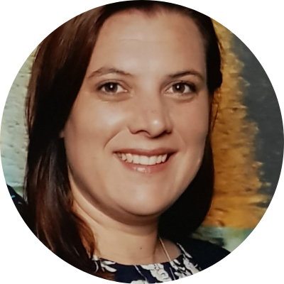 Close-up of a woman with brown hair smiling in front of a colorful background.