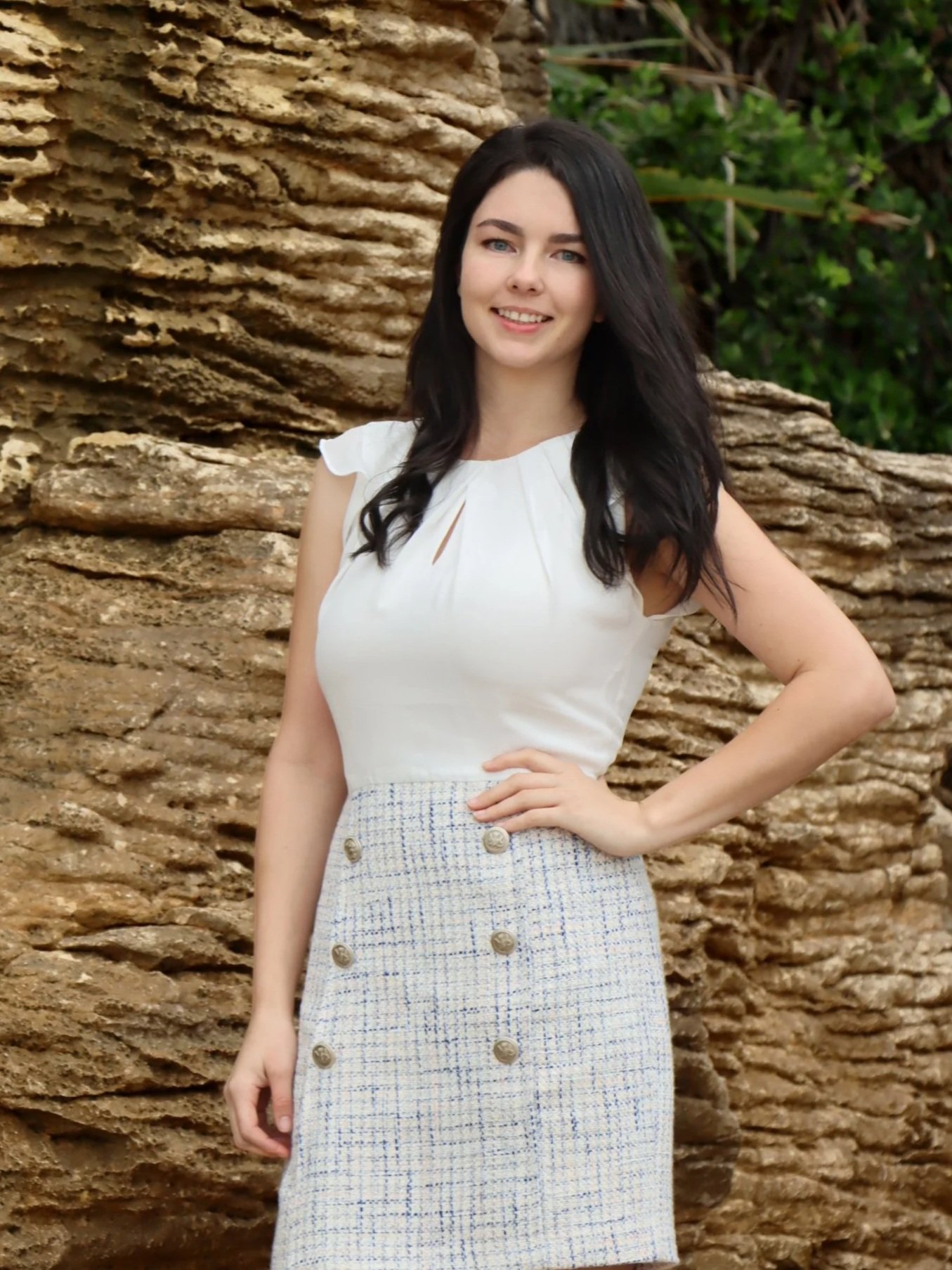 Charlotte Daun, Waipu, Langs Beach and Bream Bay real estate expert, smiling in a white top with a textured rock background.