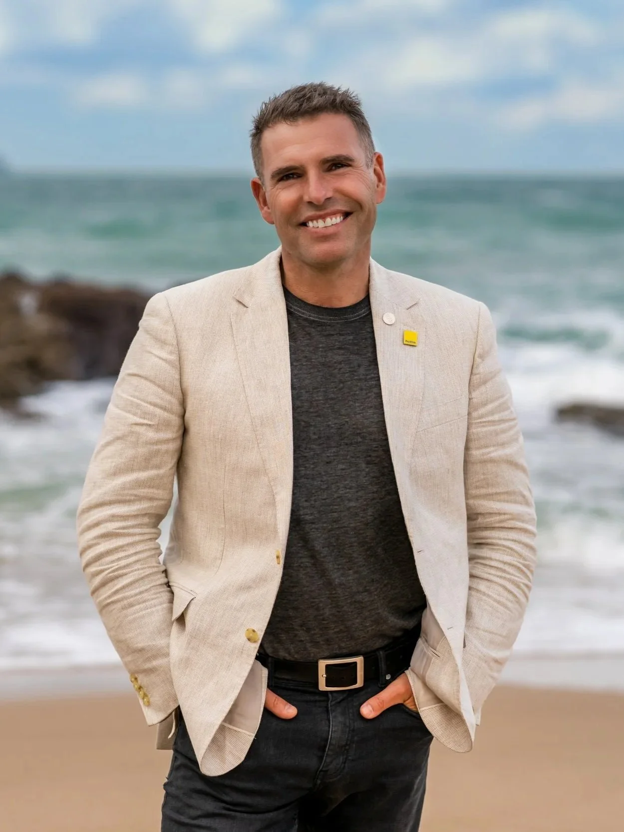 Bream Bay real estate agent James Alexander smiling on a local Langs Beach, wearing a beige blazer.