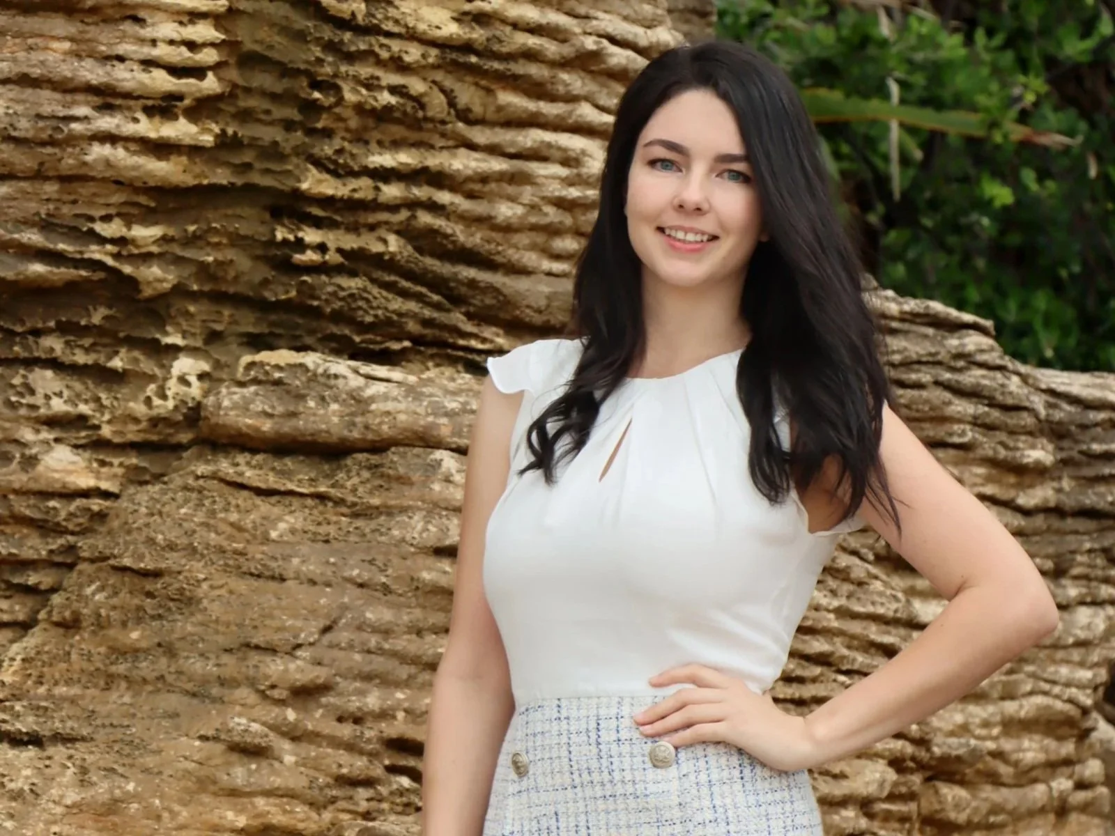 Charlotte Daun, Waipu, Langs Beach and Bream Bay real estate expert, smiling in a white top with a textured rock background.