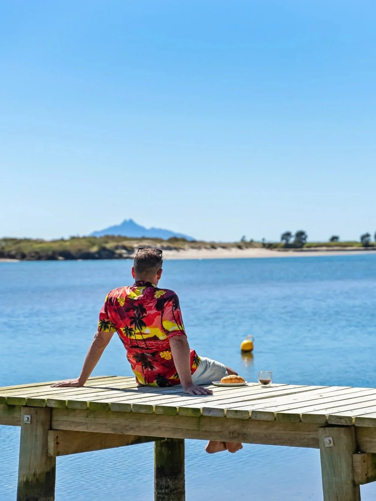 Waipu Bream Bay real estate agent James Alexander in a colorful shirt sitting on a jetty, enjoying the local Bream Bay lifestyle.