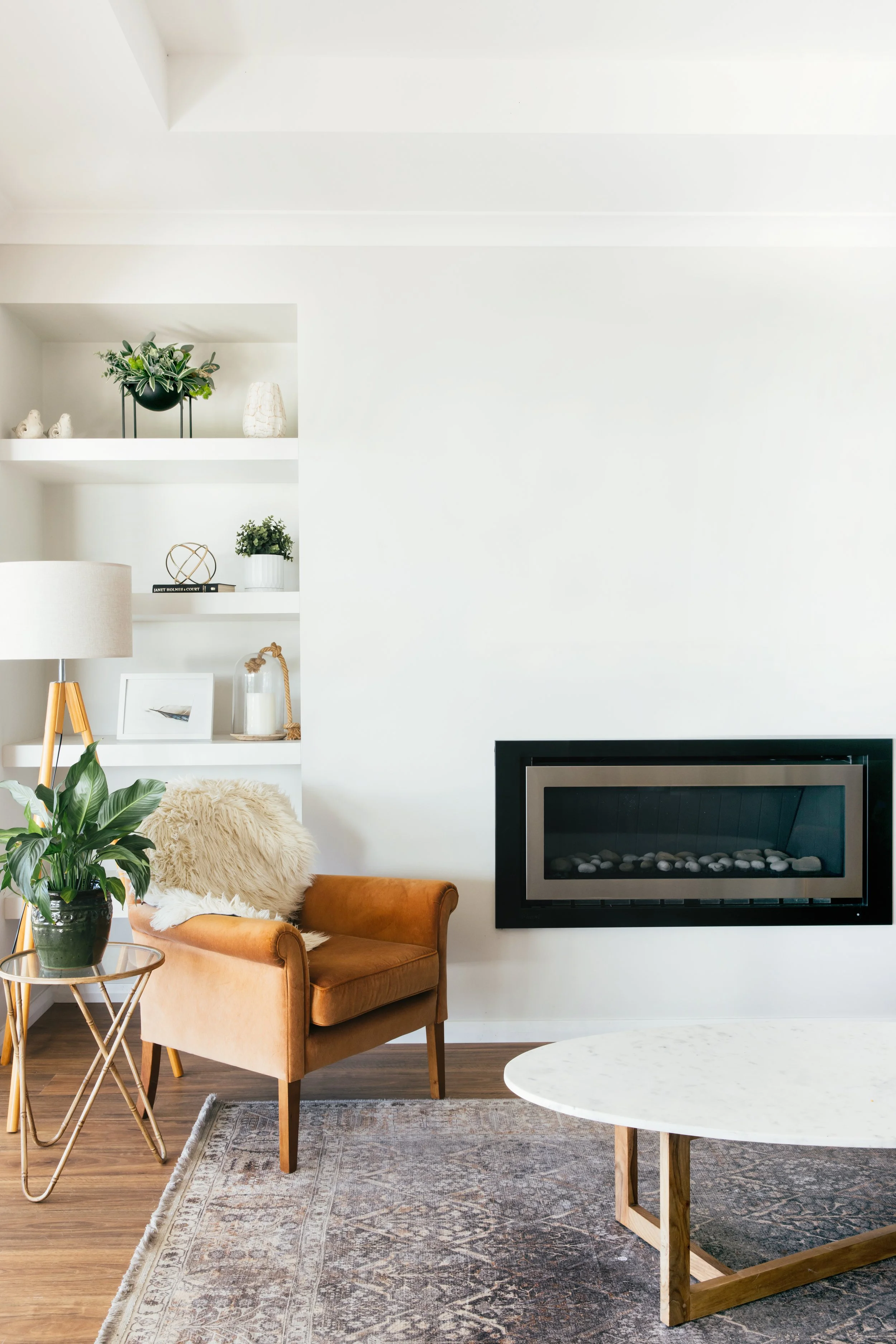 Modern Bream Bay living room staged for sale by Team James Alexander, featuring a tan leather armchair, modern fireplace, and marble coffee table.