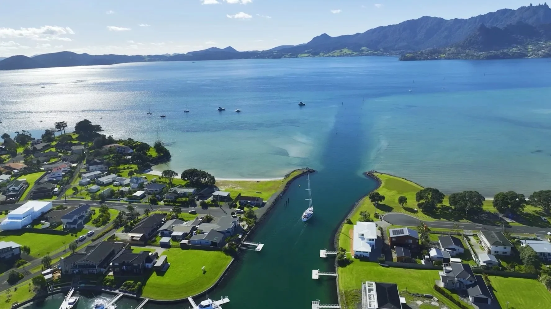 Sunny aerial view of coastal houses and boats at One Tree Point, a premier Bream Bay suburb served by real estate specialists James Alexander and Charlotte Daun.
