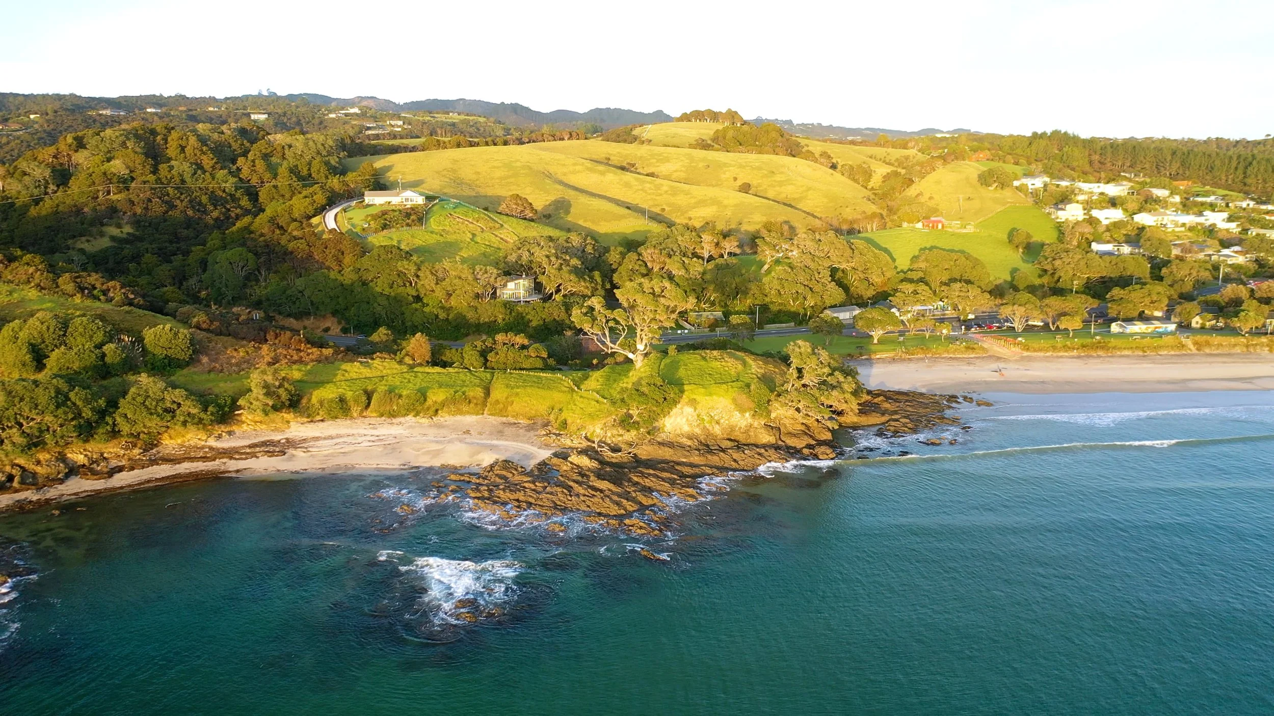 Stunning drone shot of the Waipu Cove and Bream Bay coastline, highlighting the Northland lifestyle with local real estate agents James Alexander and Charlotte Daun.