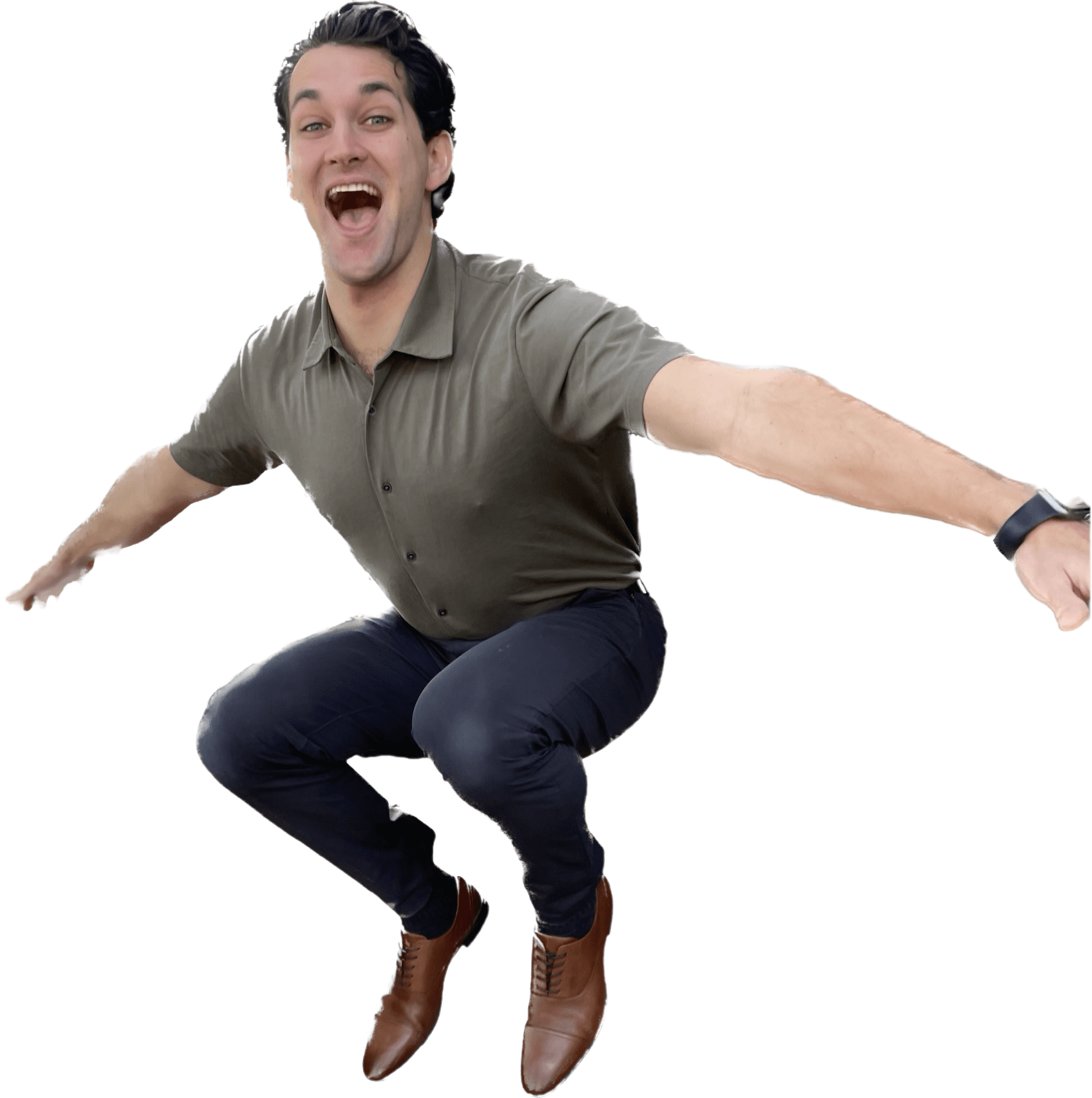 A man with dark, styled hair wearing a gray polo shirt and dark pants, smiling, in a playful pose with arms extended while balancing on one foot, wearing brown lace-up boots.