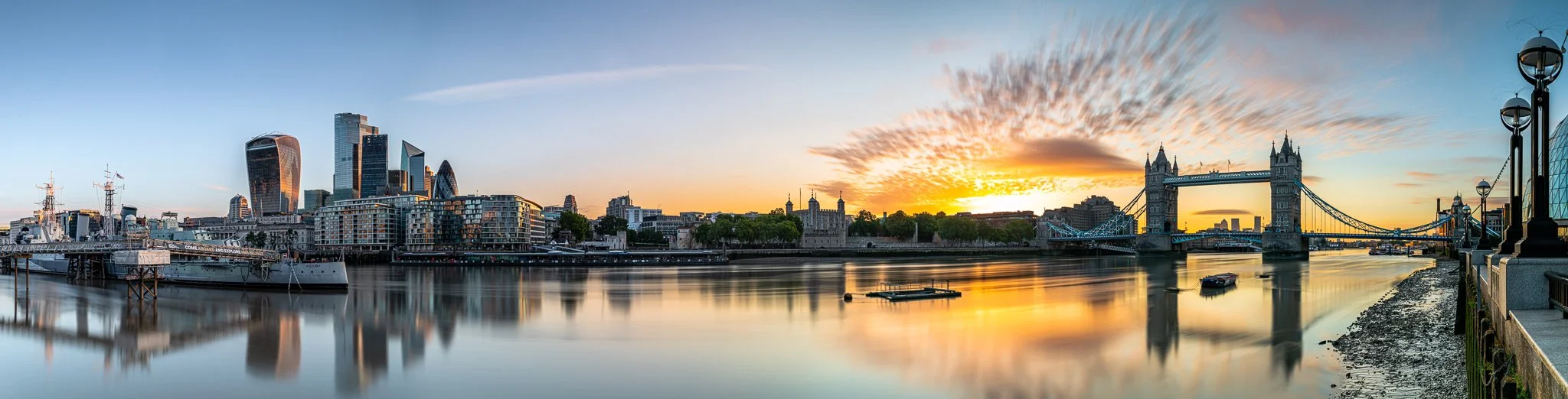 Panoramic sunrise over the Thames, where London’s skyline glows in calm dawn light. A still, reflective moment before the city awakens.