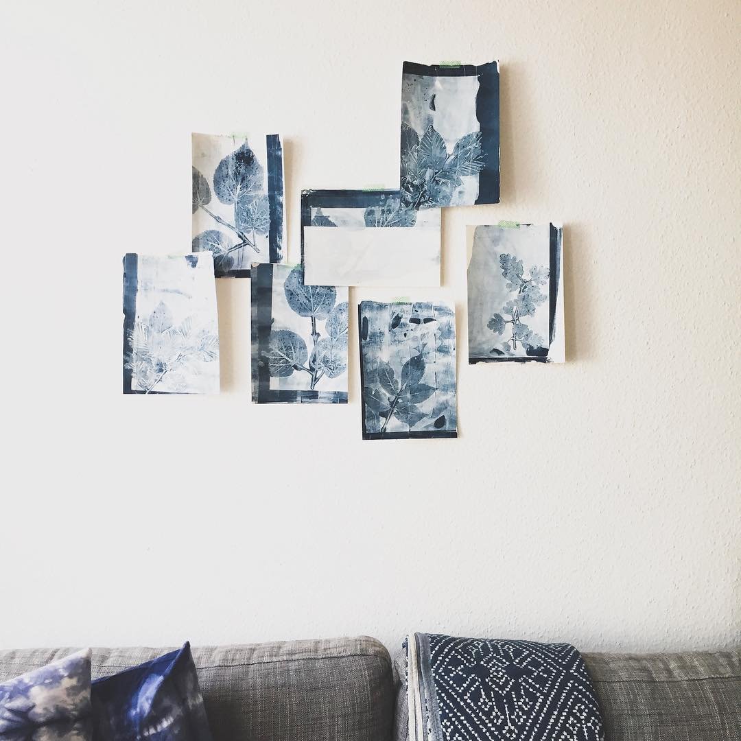 Wand mit acht Blätterringen in Blautönen über einem grauen Sofa mit Kissen.