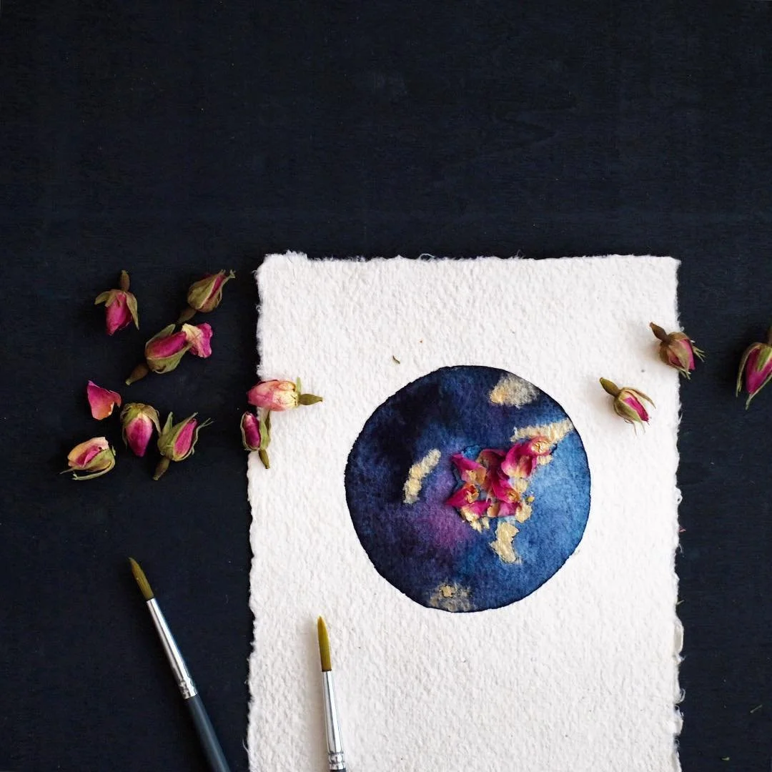 Aquarellmalerei eines blauen und goldfarbenen Mondes auf dickem, weißen Papier.