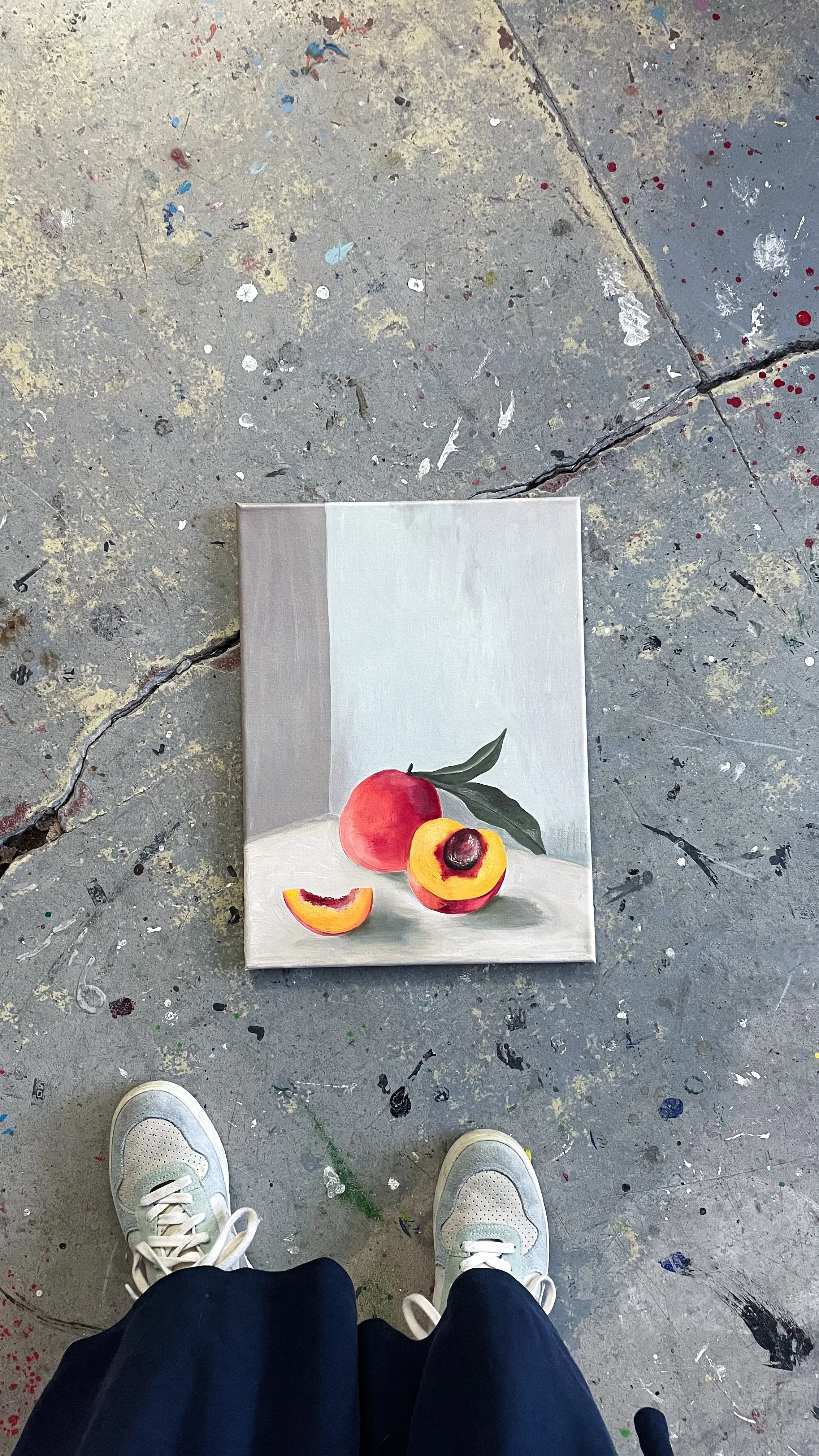 Palette mit einer stilllebenähnlichen Darstellung zweier Pfirsiche, einer davon halbiert, auf einem weißen Hintergrund.