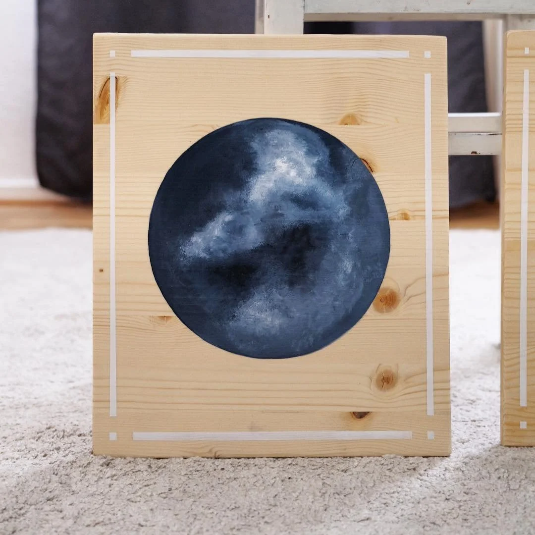 Holzrahmen mit gemalten Monddetails, auf einem Teppichboden