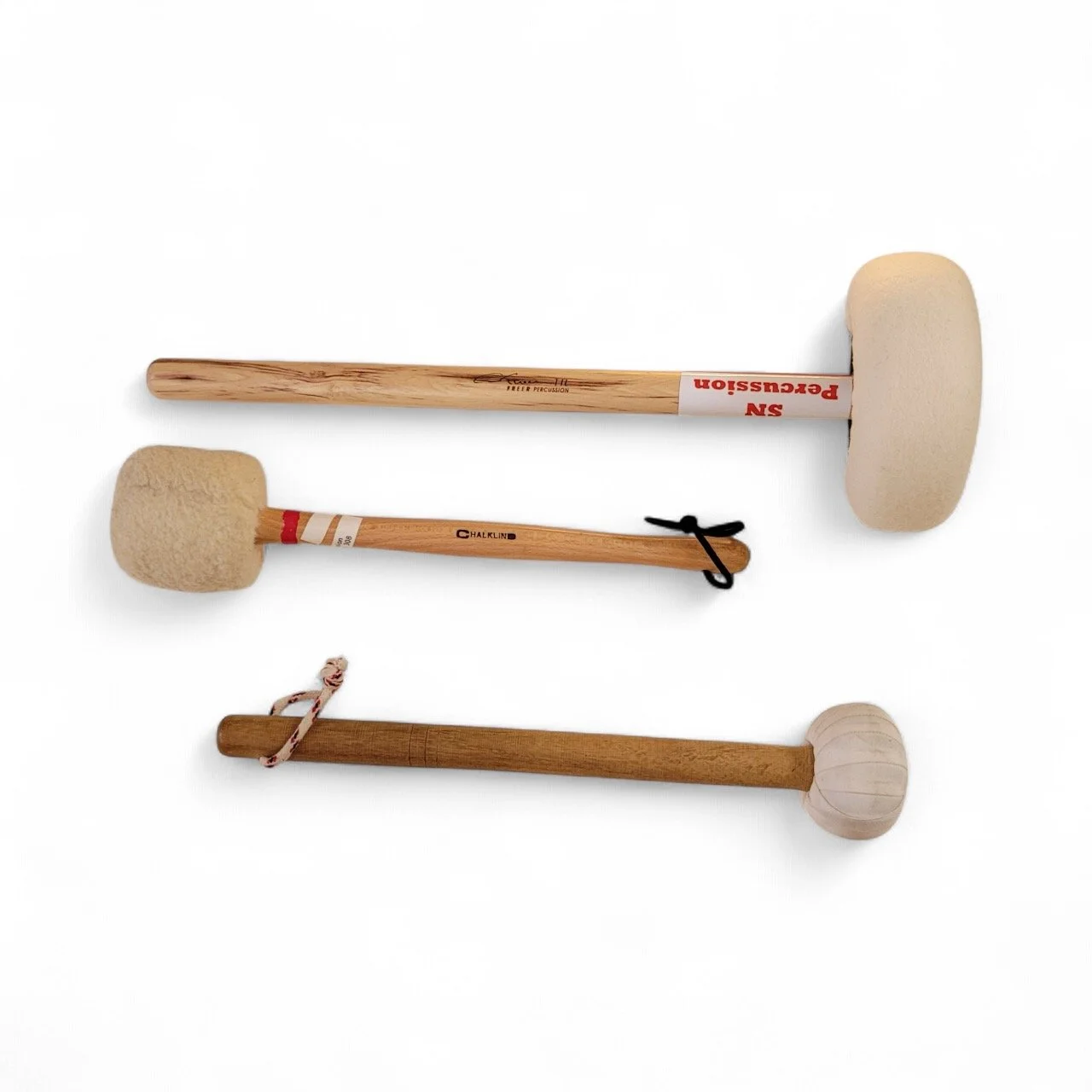 Three drum mallets with different heads placed horizontally on a white background.