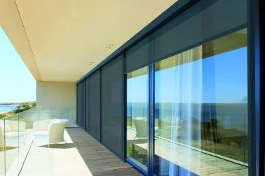 Balkon mit Sitzgelegenheiten und Blick auf das Meer durch große Glasfenster