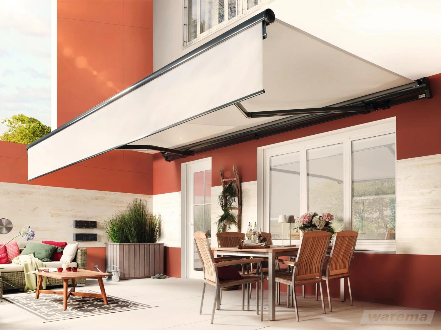 Balkondeck mit faltbarem Markise, Gartenmöbeln, Pflanzen und Dekoration auf einer Terrasse.