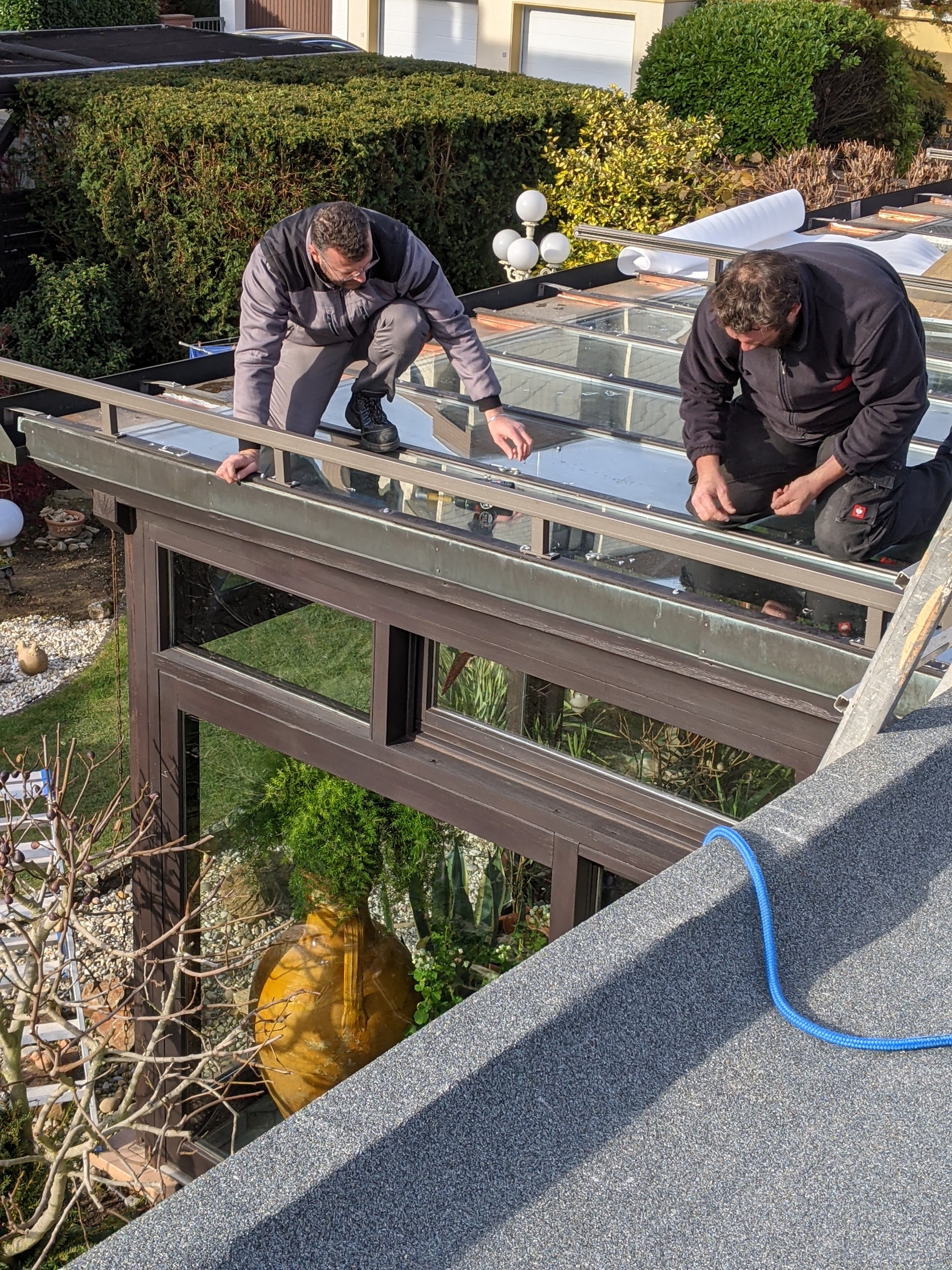 Zwei Männer reparieren die Dachverglasung eines Hauses auf dem Dach eines Gebäudes.