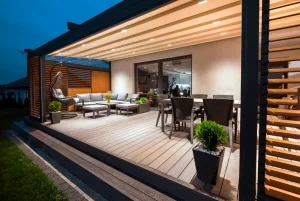 Moderne Terrasse mit Sitzbereich, Esstisch, Pflanzen und Holzverkleidung bei Nacht