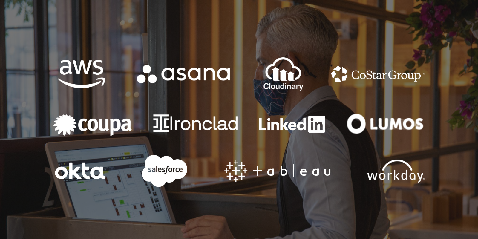 A man wearing a face mask, standing at a computer, with various company logos overlayed on the image.