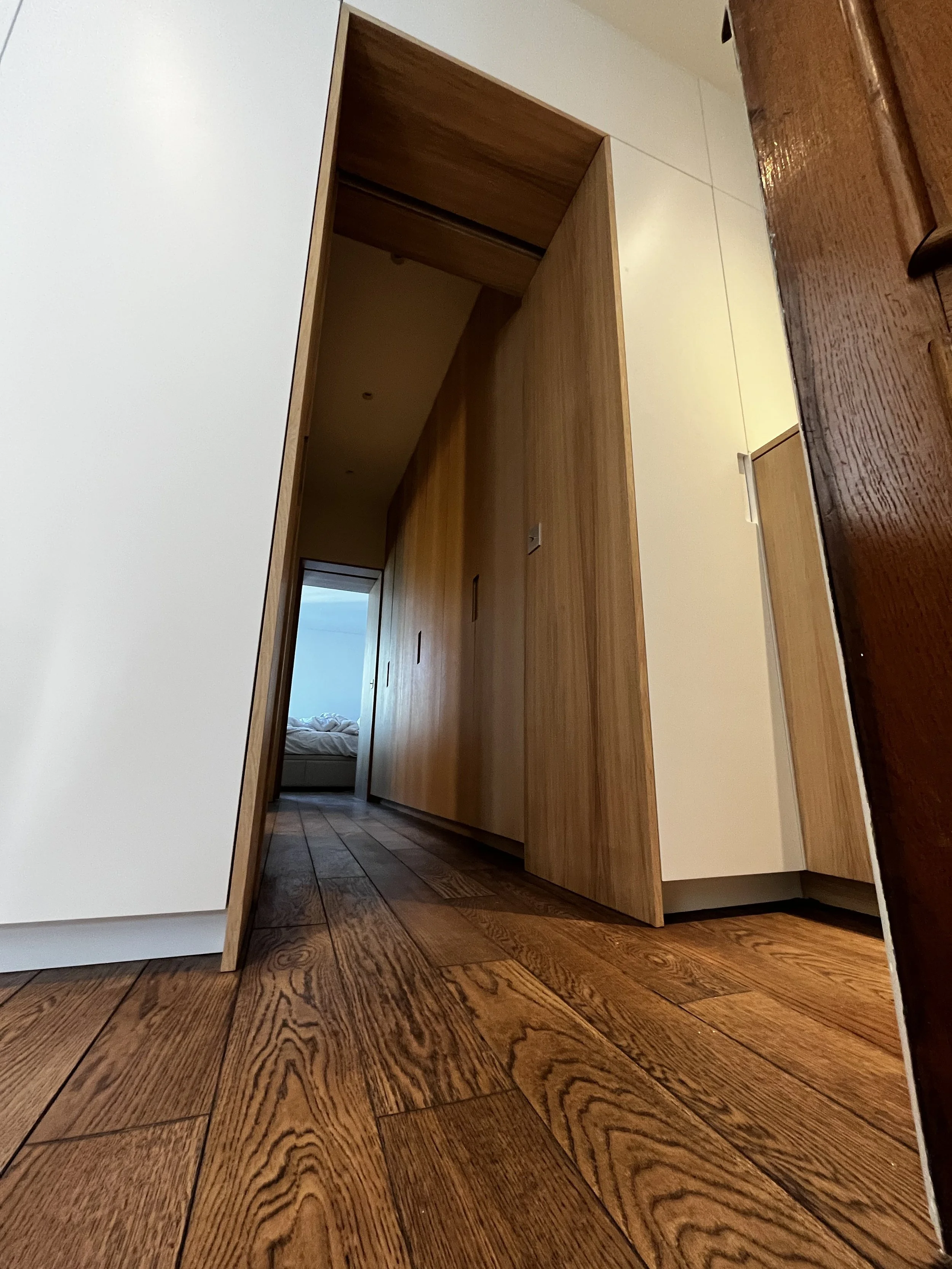 Une porte en bois entrouverte dans une maison, avec un plancher en bois foncé.