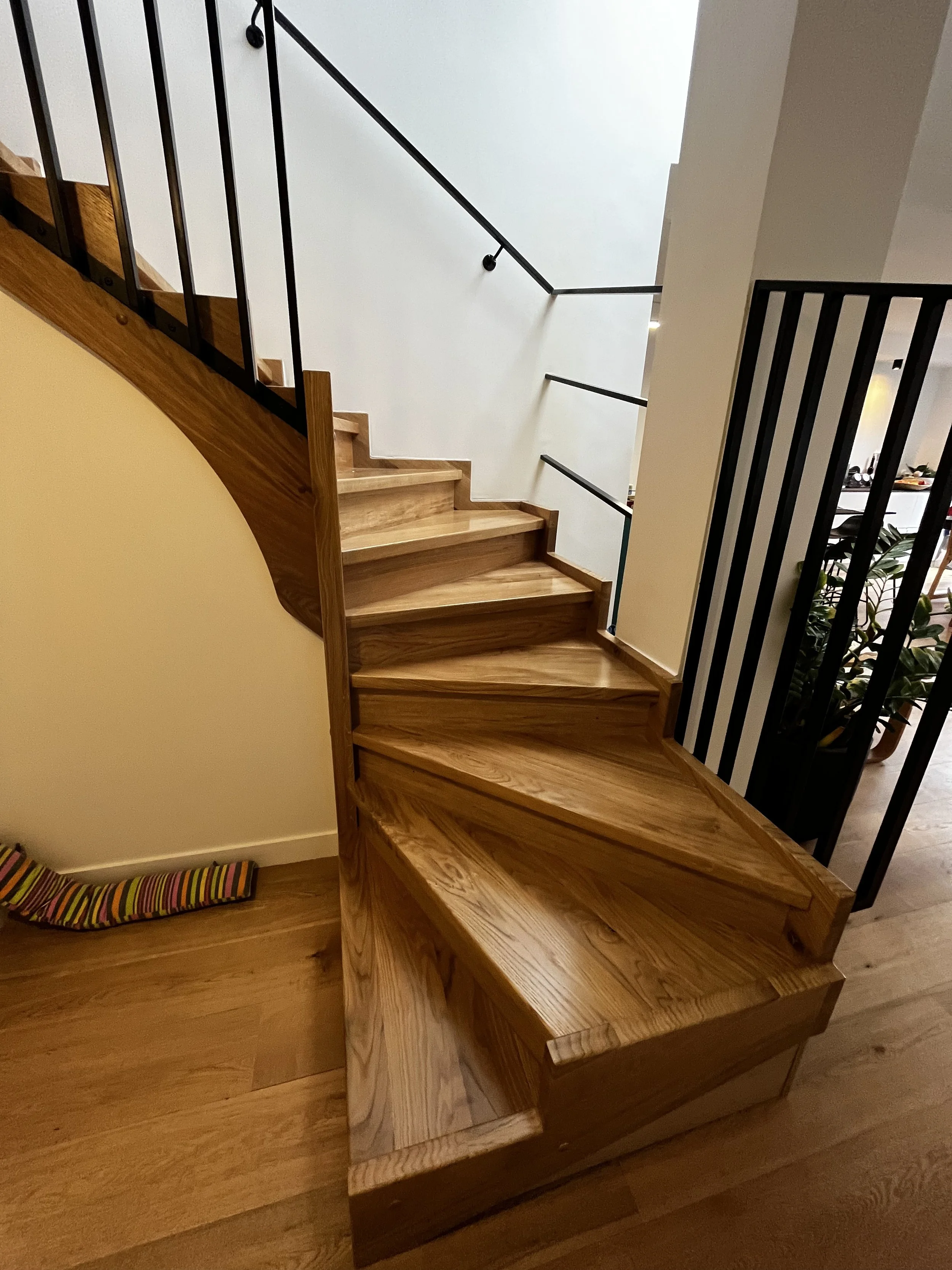 Escalier en bois avec rampe noire dans une maison moderne, vue de dessous.