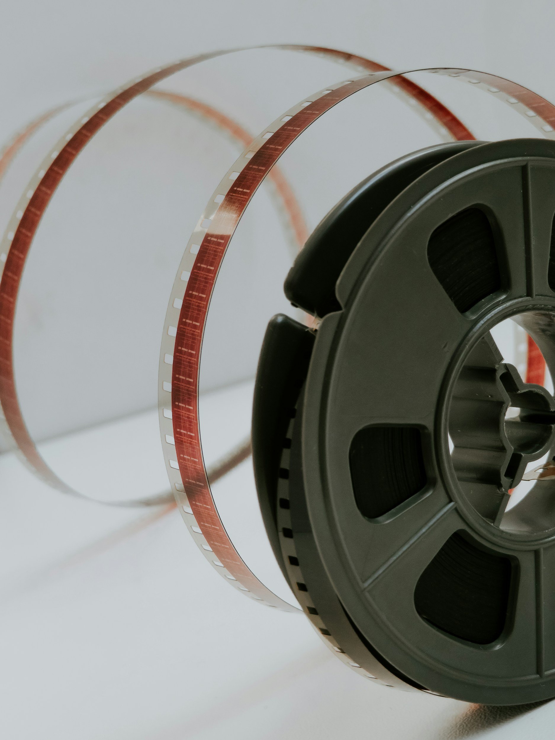 Close-up of a film reel with loose strip of photographic film hanging from it.