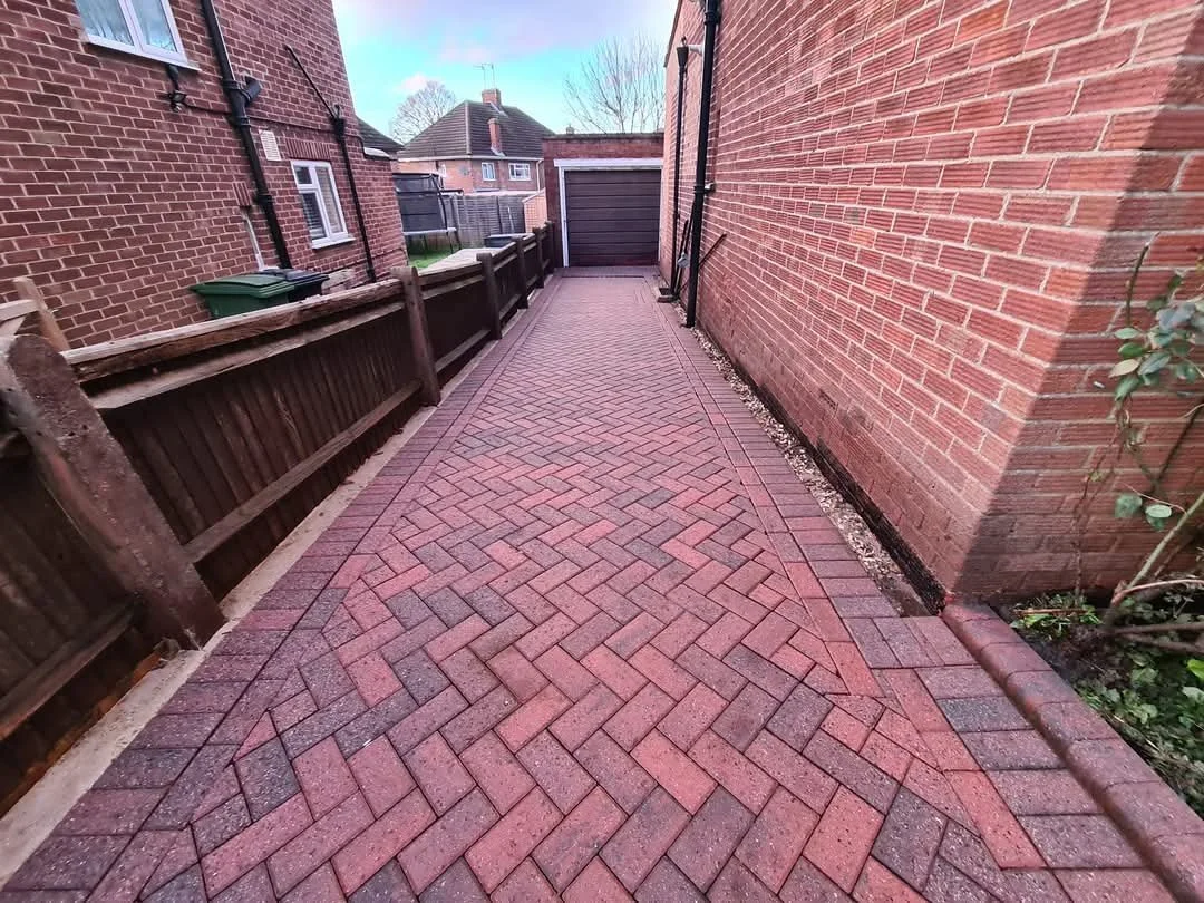 Clean and restored red herringbone block paving side driveway after deep pressure washing and re-sanding in Woodley.