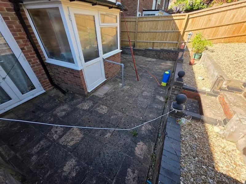 Dirty, moss covered back garden patio slabs before professional black spot removal and deep jet washing in Woodley.