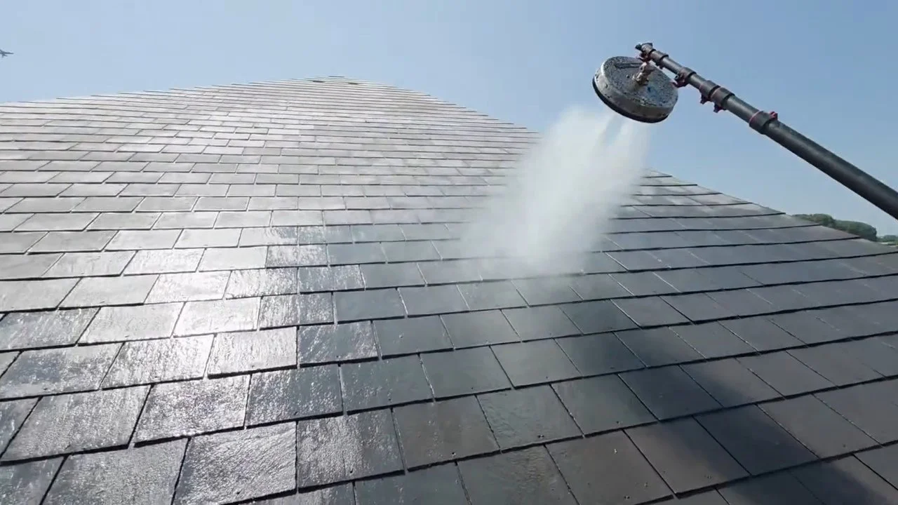 Power washing a dark gray shingle roof with a pressure washer