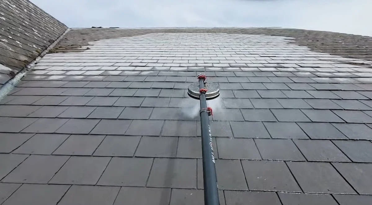 Professional commercial roof cleaning machine actively washing flat grey slate tiles on a large property in Wokingham.
