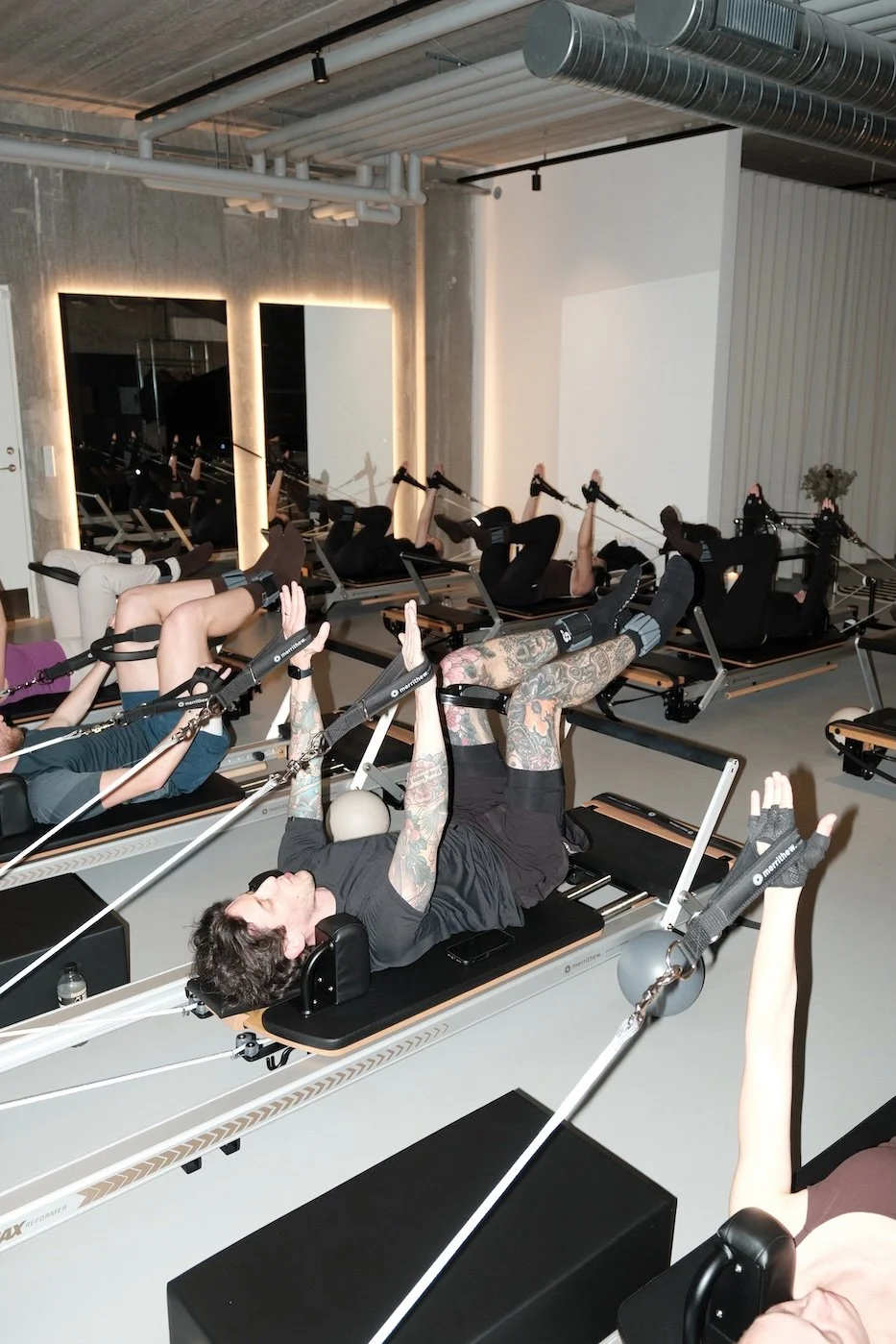 People participating in a reformer Pilates class using Pilates reformer machines in a modern studio.