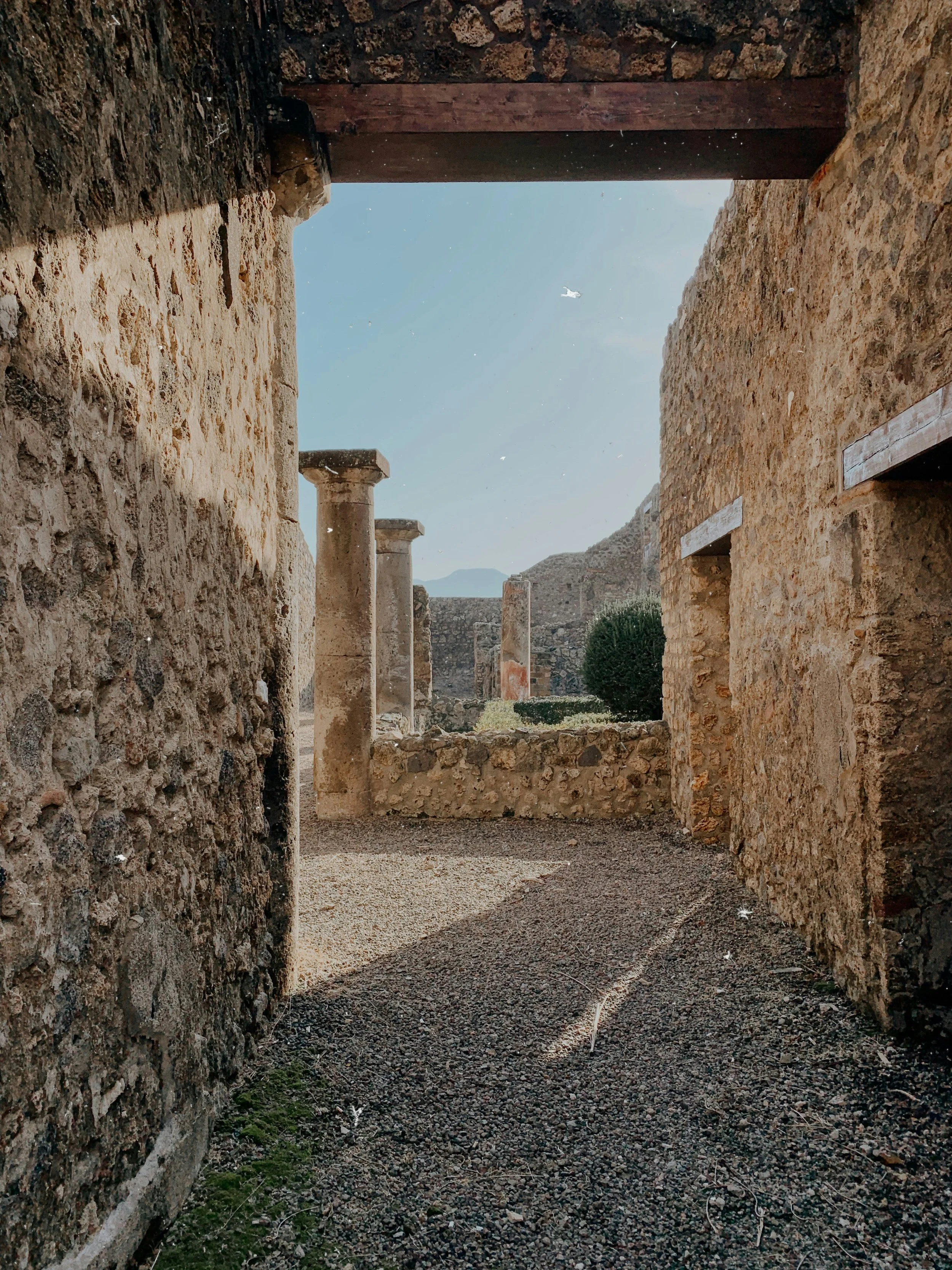Ancient stone ruins with columns and stone walls, sunny sky, and distant mountains.