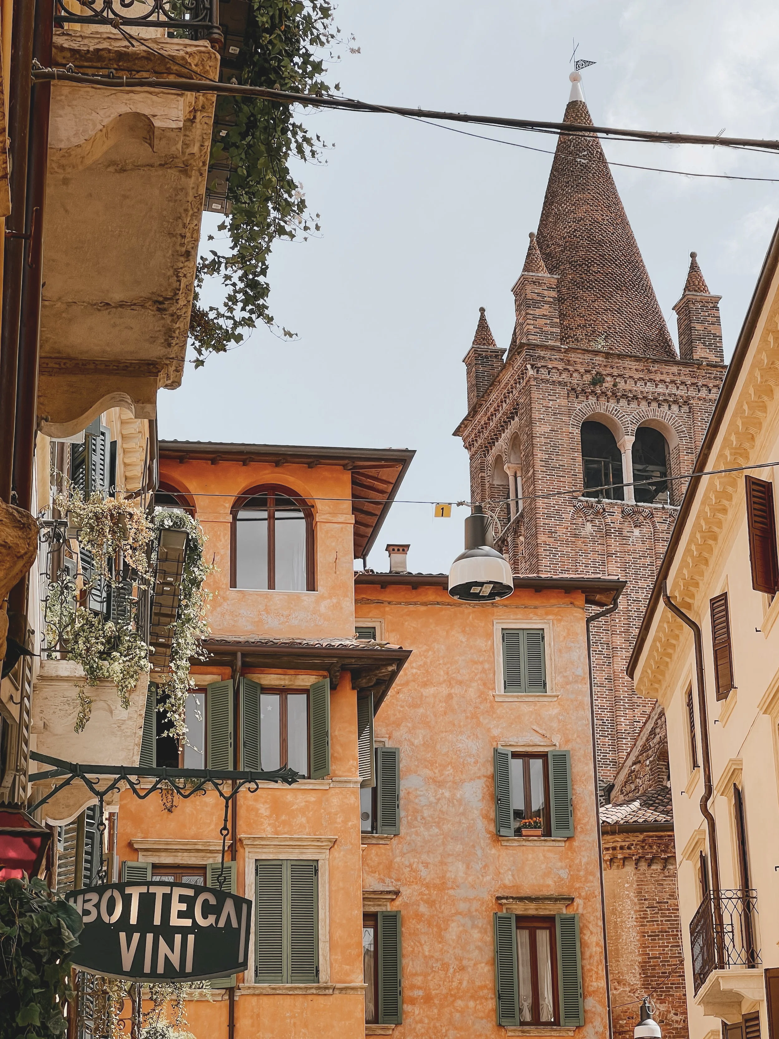 Historic Italian buildings with colorful facades, green shutters, and a church tower with a conical roof