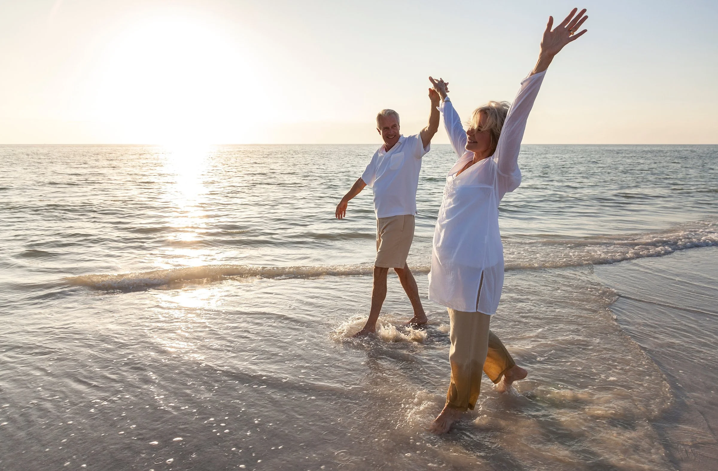 Couple de seniors plein d'énergie marchant au bord de la mer au coucher du soleil, évoquant la vitalité et la longévité, Centre NEORA, Plan de Campagne