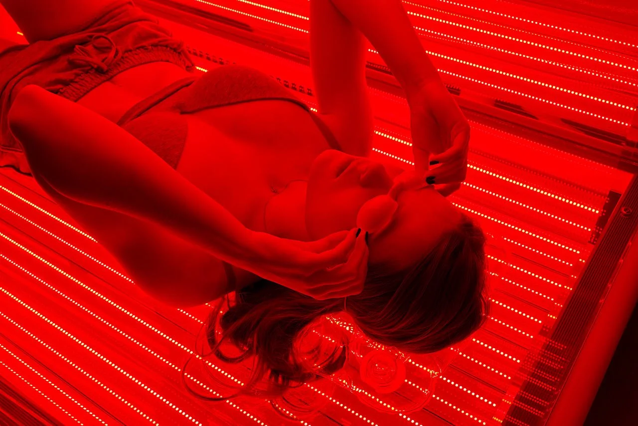 Cliente allongée en cabine LED corps entier sous la lumière rouge, séance pour la fibromyalgie, la fatigue chronique et le Covid long, Centre NEORA, Plan de Campagne
