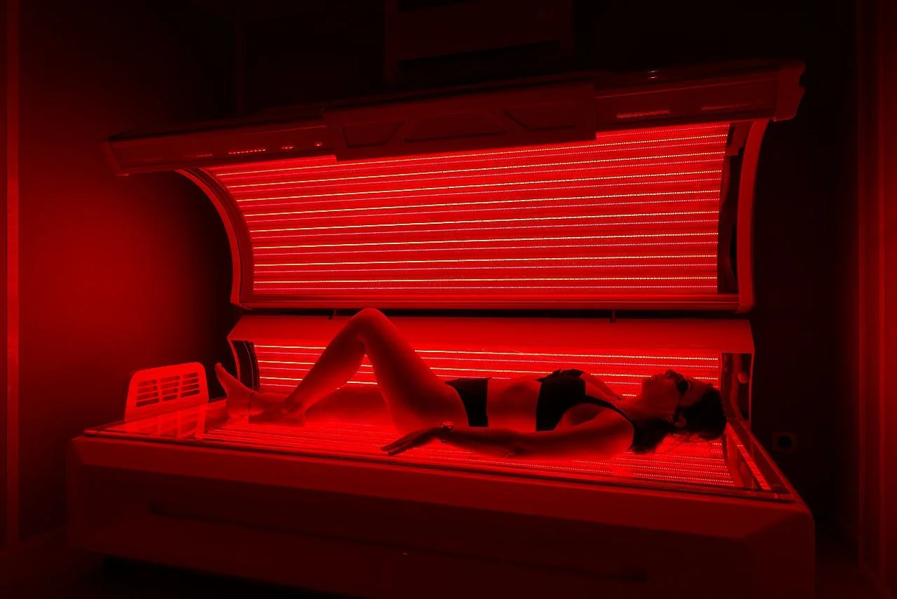 Cliente allongée en cabine LED corps entier sous la lumière rouge, séance pour le bien-être à la ménopause, Centre NEORA, Plan de Campagne