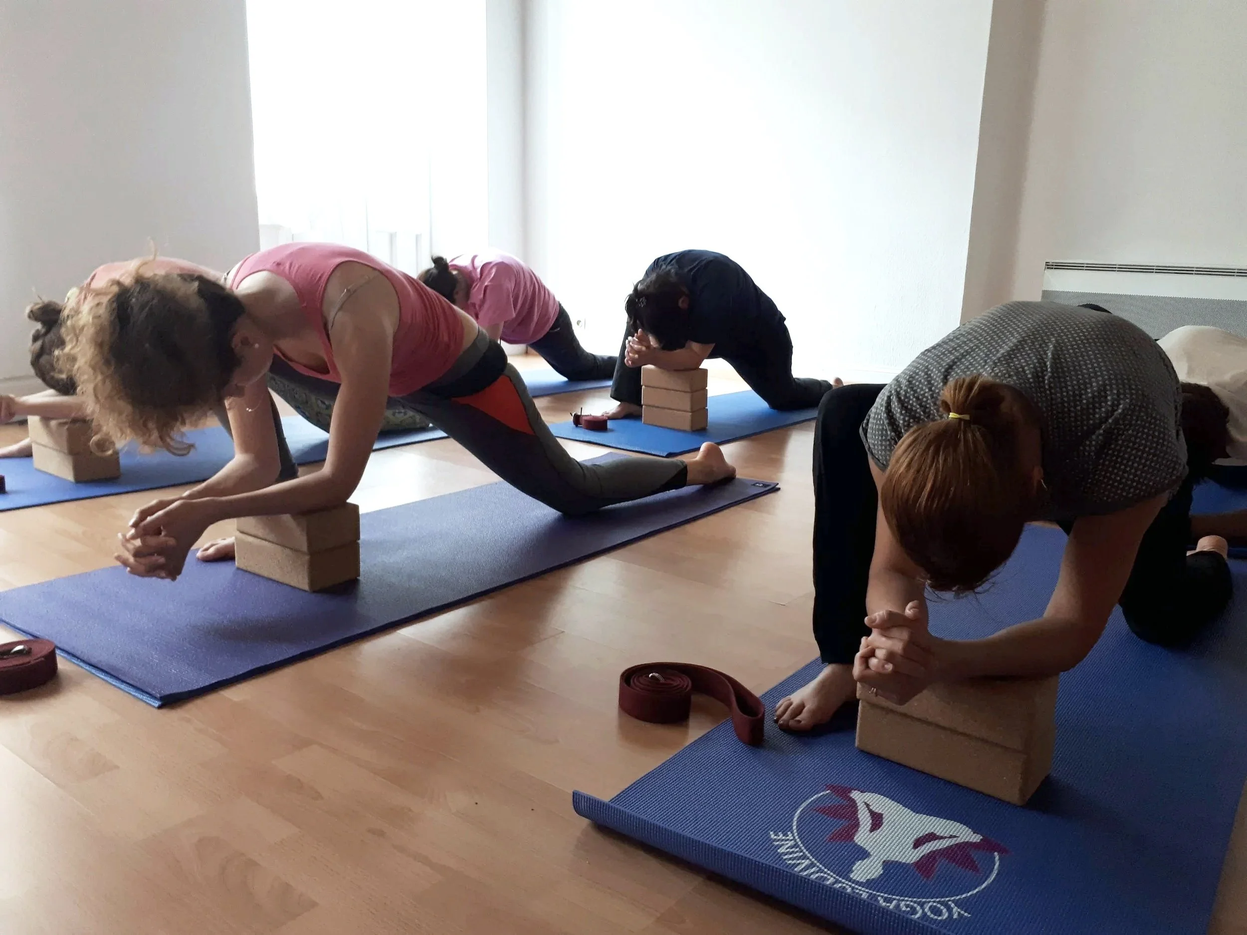 Groupe de personnes participant à un cours de yoga, pratiquant la posture du chameau en appui sur des blocs