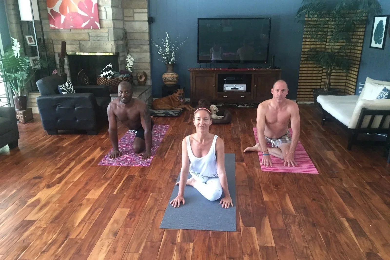 Quatre personnes faisant du yoga dans un salon, avec deux hommes, une femme et un chien