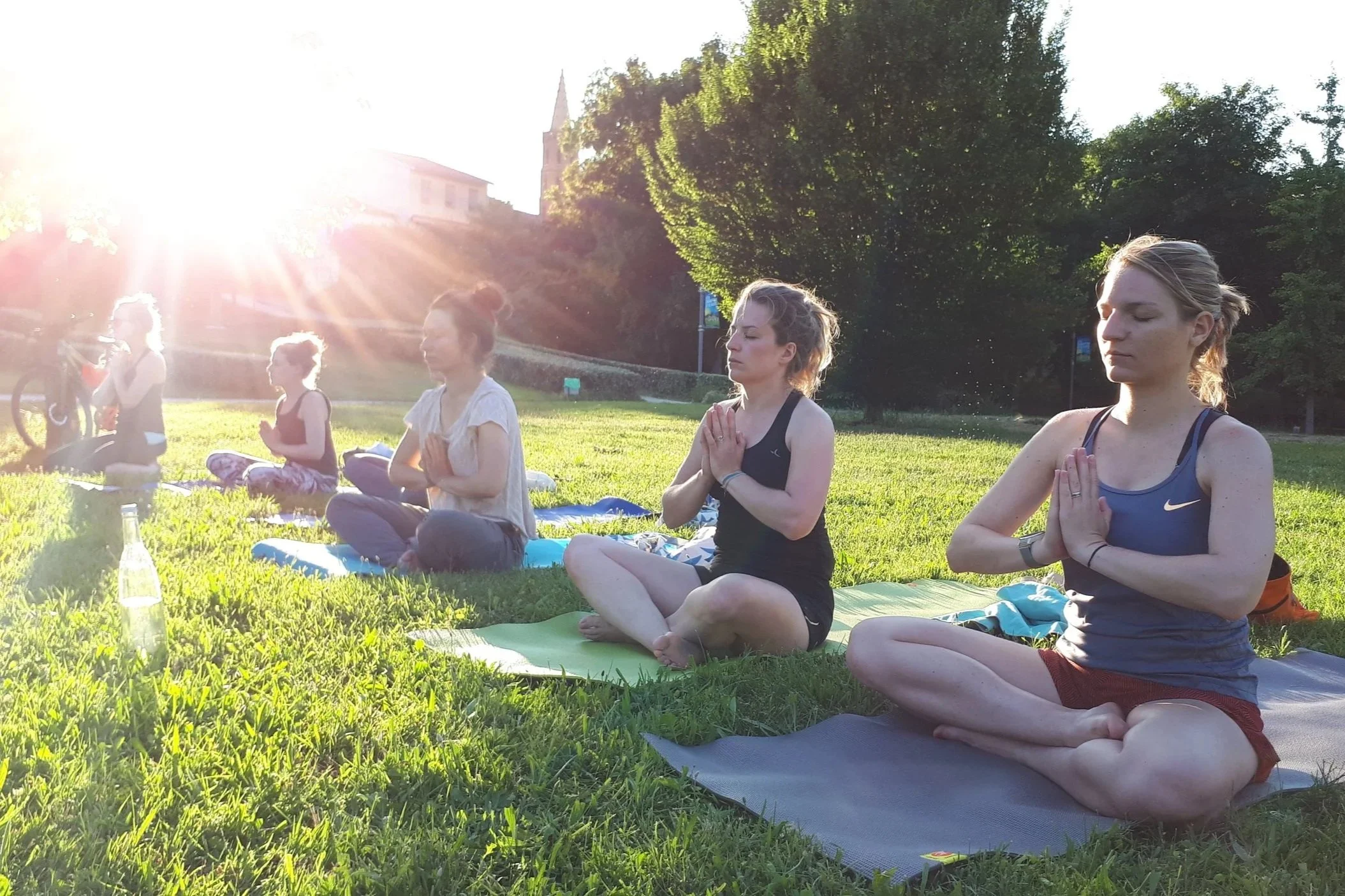 Groupe de femmes méditant en plein air lors d'une séance de yoga ou de méditation au lever ou coucher du soleil dans un parc vert