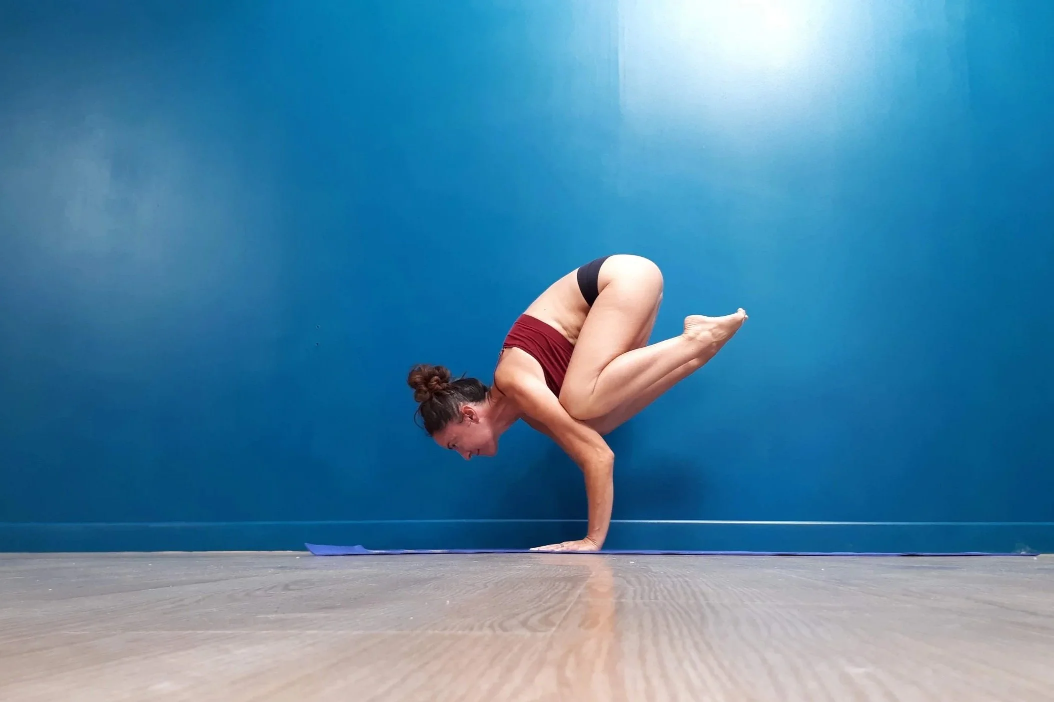 Femme pratiquant la posture de yoga explore la concentration et l'équilibre sur un tapis de yoga en intérieur.