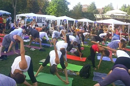 Groupe de personnes faisant du yoga en plein air sur des tapis colorés.