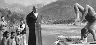 Groupe d'hommes et de garçons au bord de l'eau, avec une personne en train de faire de la gymnastique ou de la danse