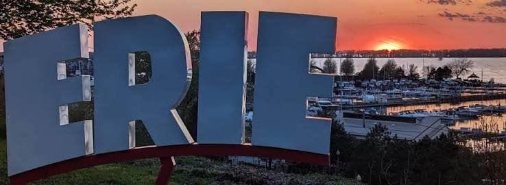 Large blue letters spelling 'ERIE' with a marina and sunset in the background.