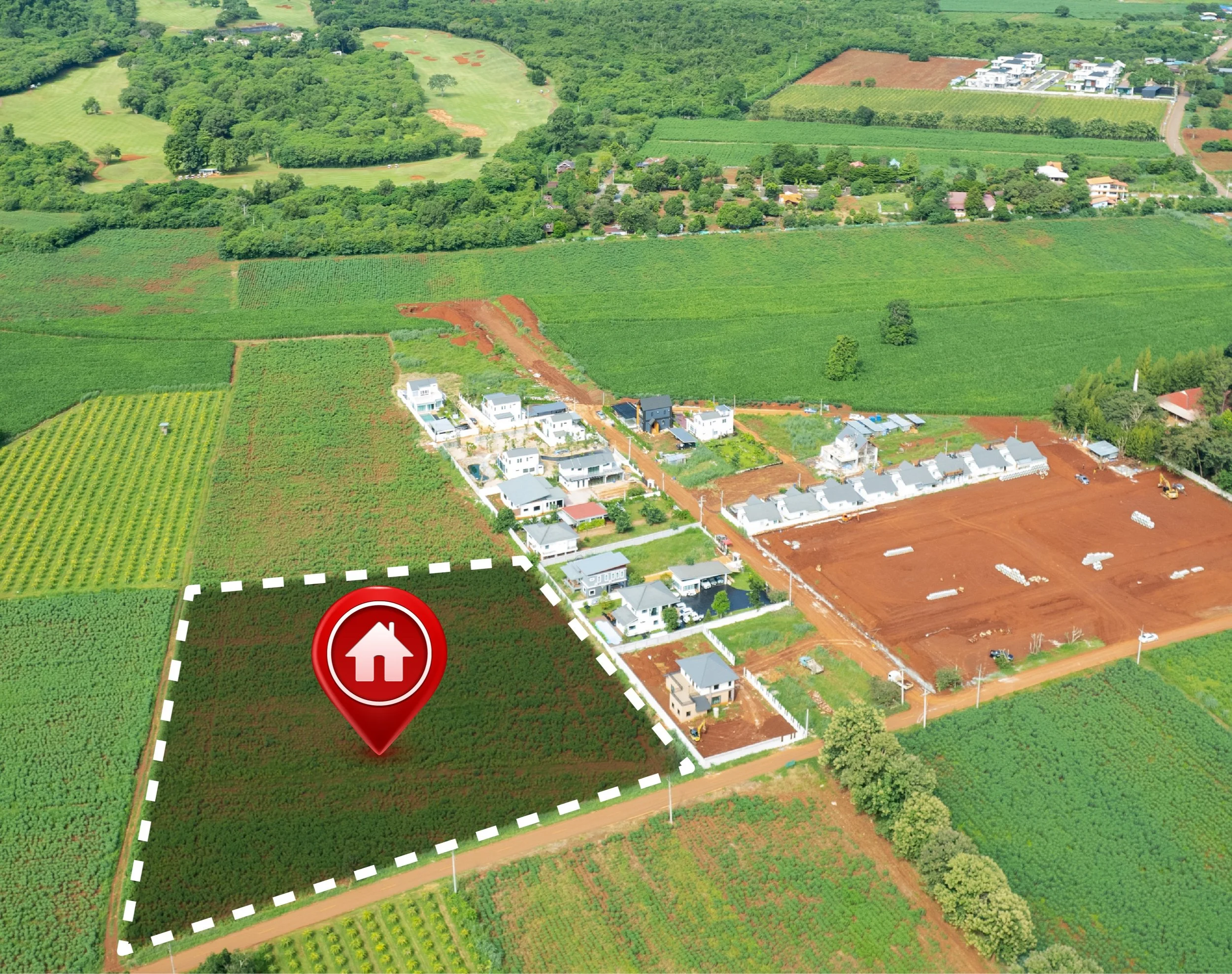 Aerial view of a rural area with a mix of farmland, residential houses, and ongoing construction. A specific plot of land is outlined with a white dashed line and marked with a red house icon.