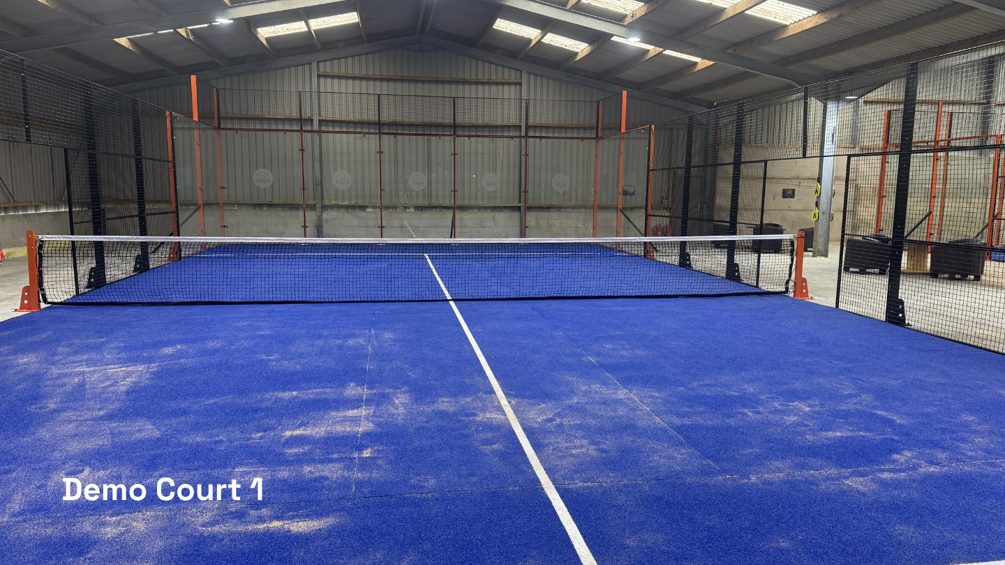 An indoor pickleball court with a blue surface, white markings, and a net in the middle. The court is labeled "Demo Court 1" in the bottom left corner.