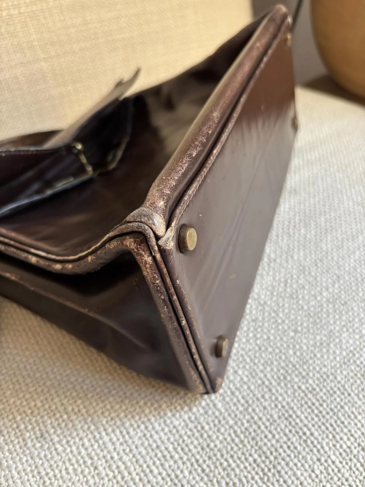 Sac Hermès Kelly vintage, poignée cassée et cuir usé. Angles et coins abimés.