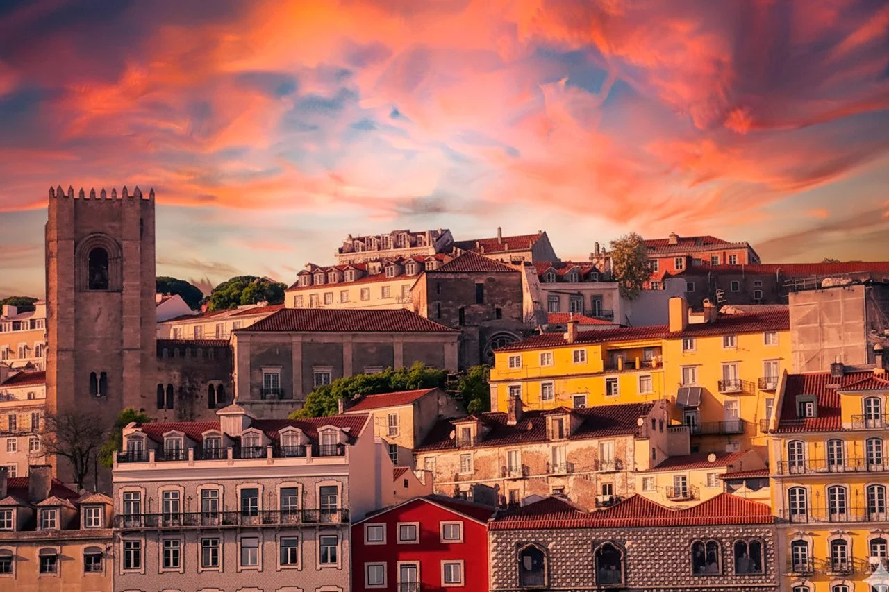 Cena de uma cidade com edifícios coloridos sob um céu com nuvens rosadas ao pôr do sol.