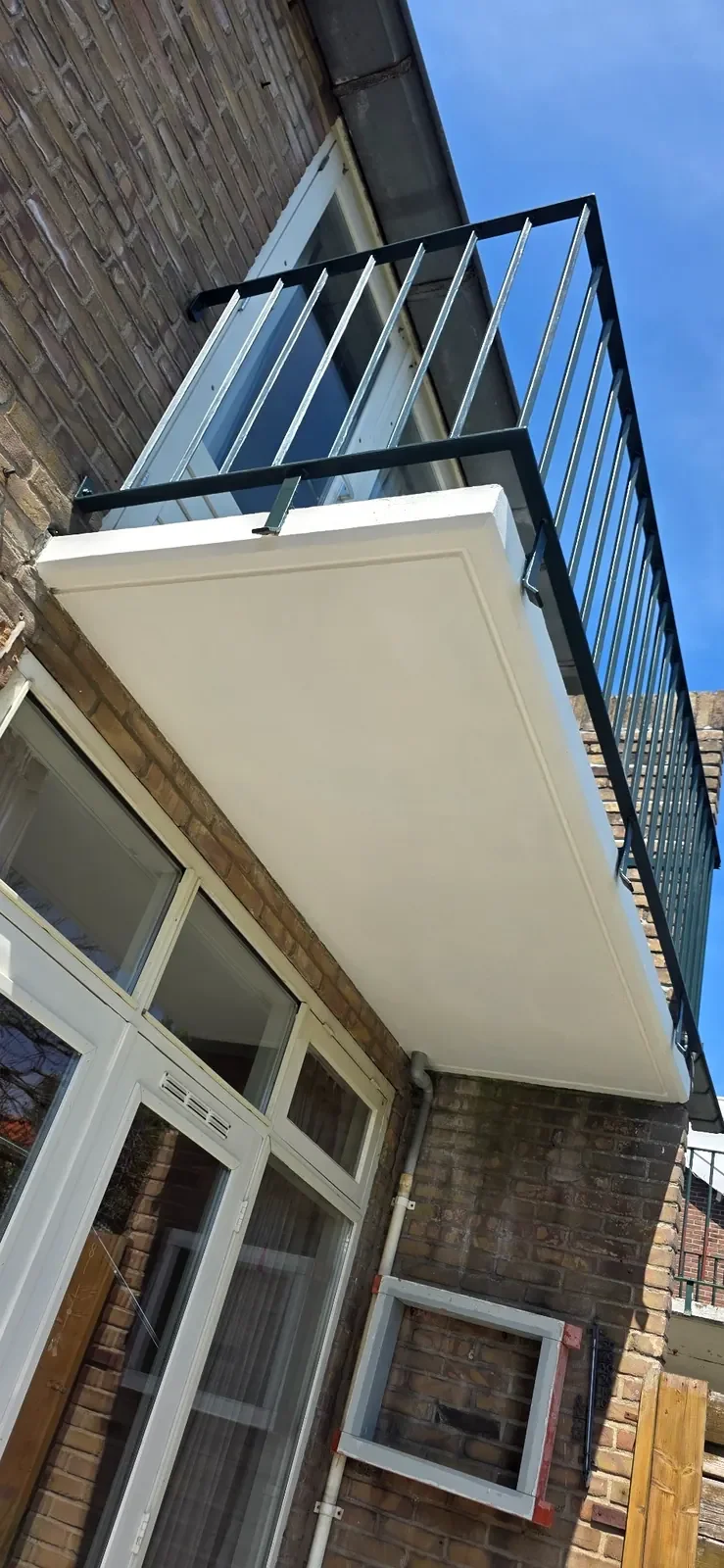 Gecoate onderzijde van een gerenoveerd betonnen balkon met nette afwerking.